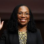 Ketanji Brown Jackson lift her hand as she is being sworn in to testify on Capitol Hill.