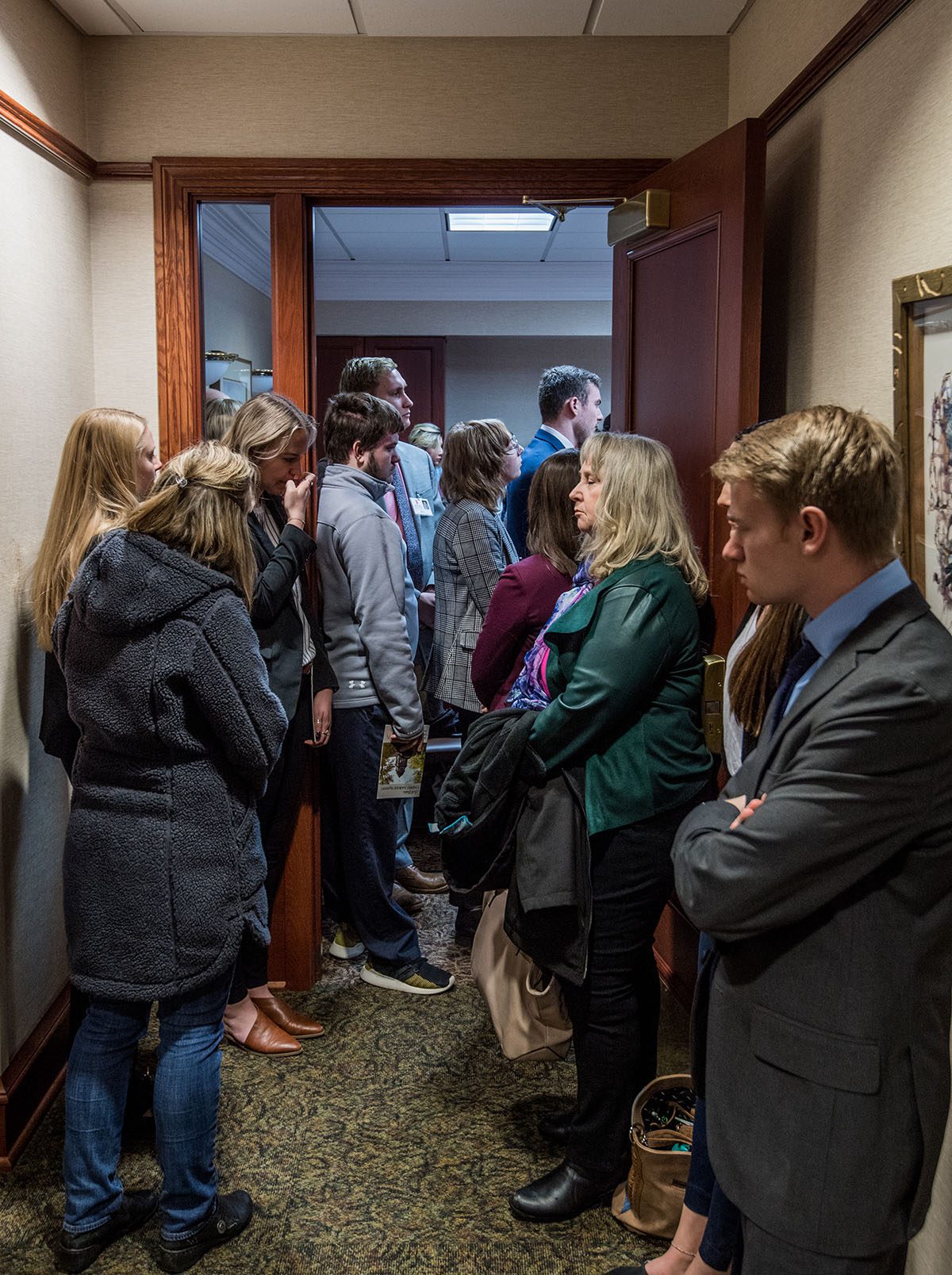 A crowd of people stand outside a door.