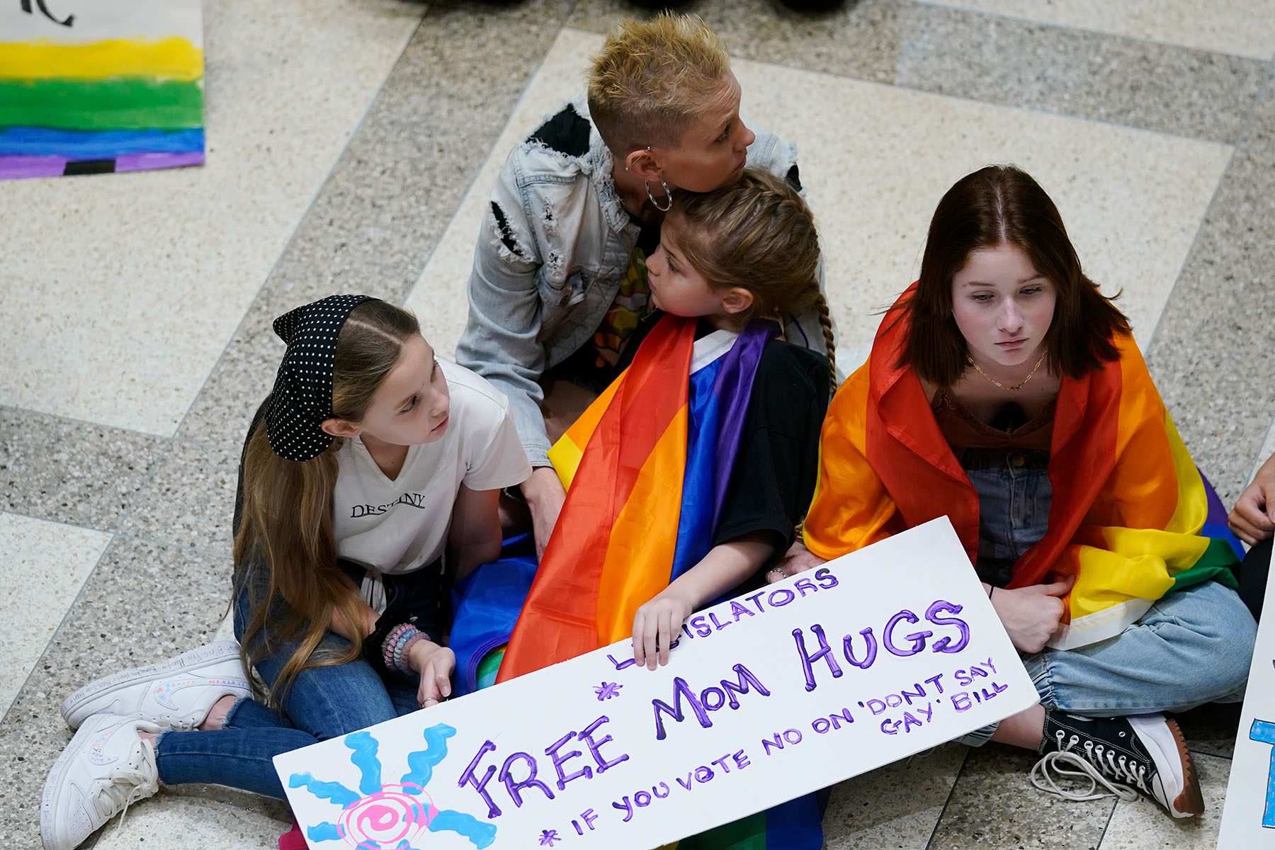 A mother hugs her child as they protest the "don't say gay" bill inside the Florida State Capitol.