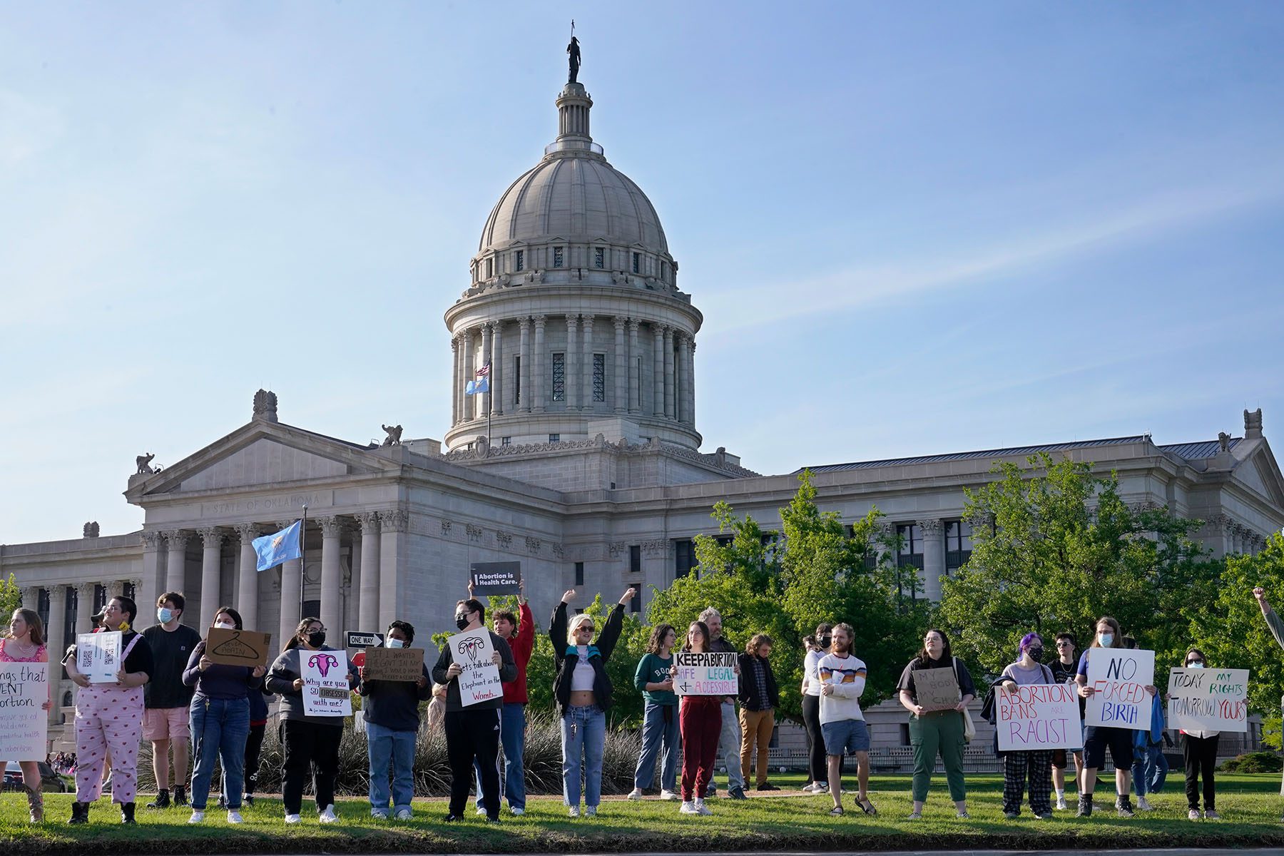 Abortion-rights supporters rally in front of the State Capitol. Signs read "Abortion Bans are Racist" and "No Forced Birth."