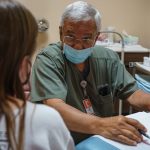 A doctor wearing a face mask speaks with a woman seeking an abortion.