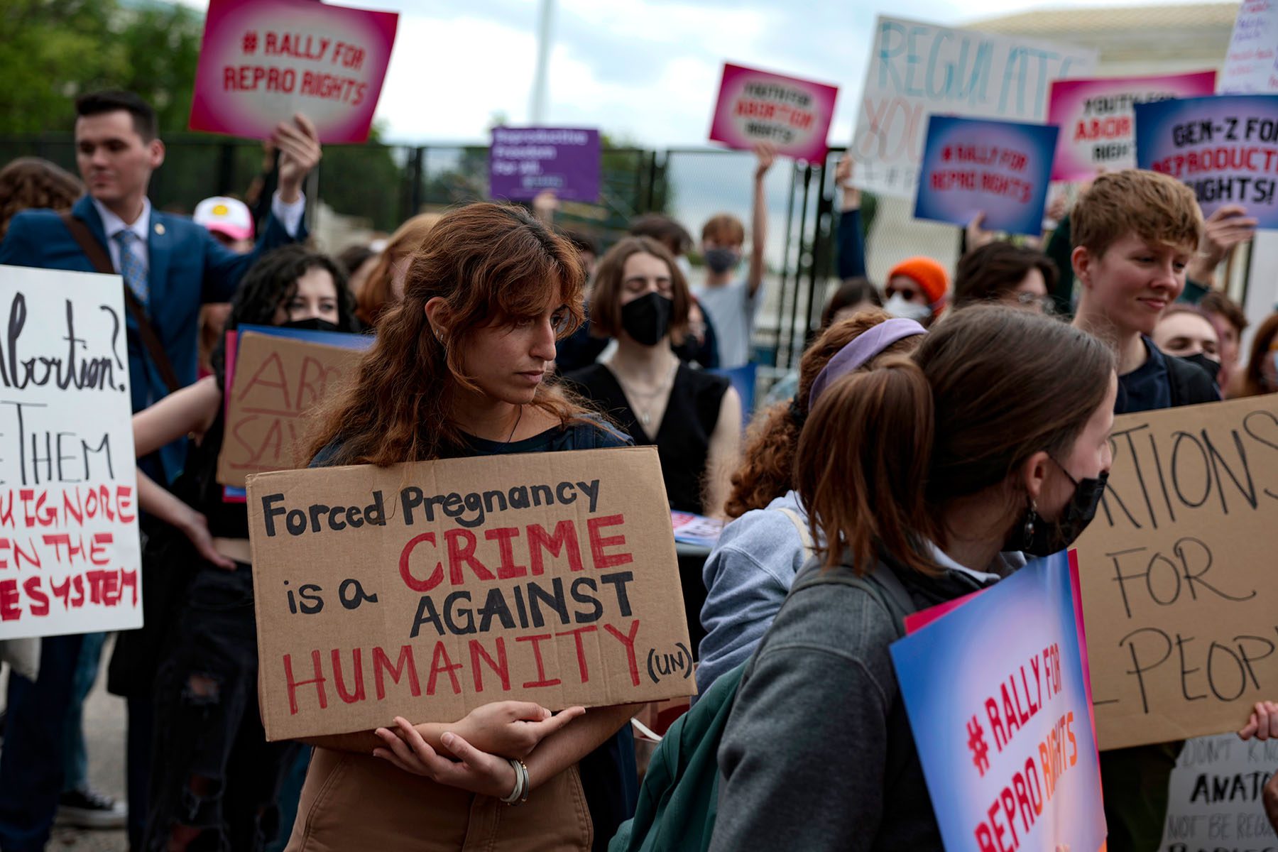 A woman holds a sign that reads "Forced Pregnancy is a Crime Against Humanity" as she protests in front of the Supreme Court.