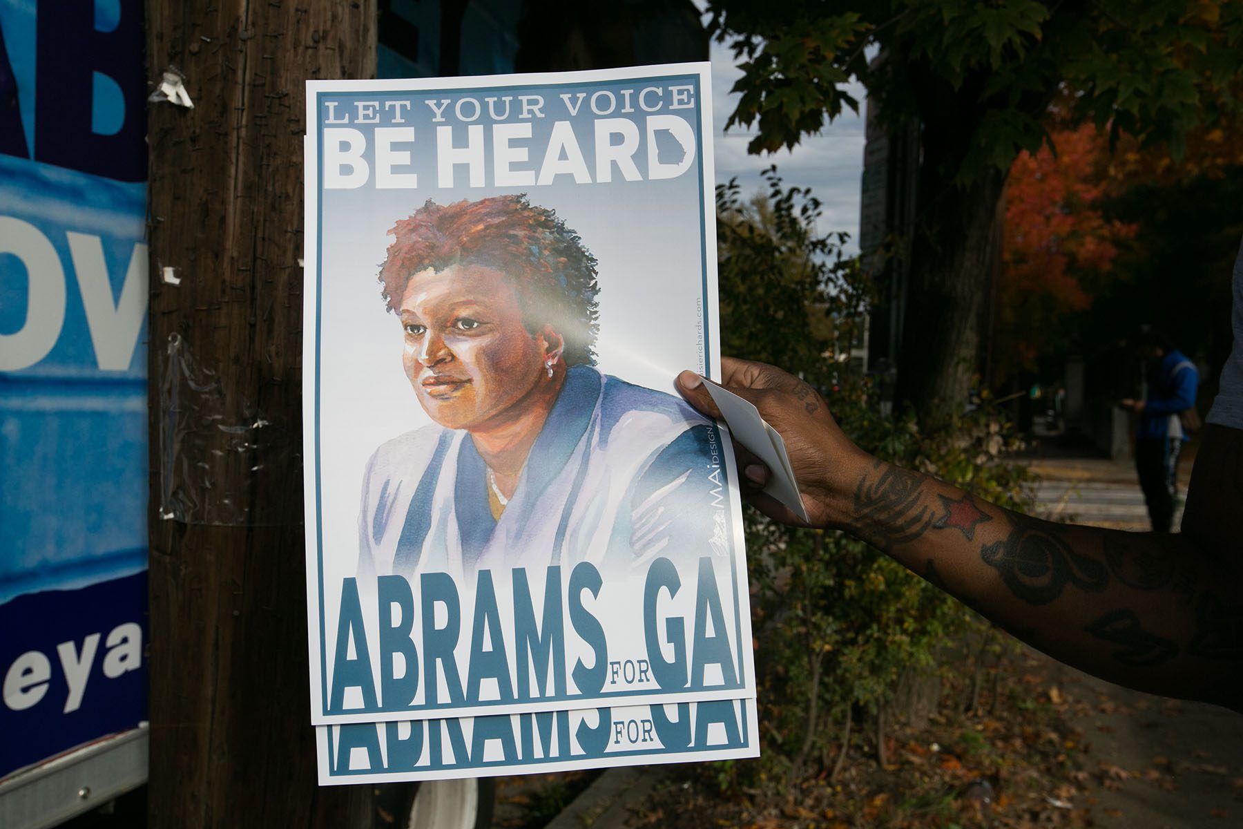 A supporter holds a campaign poster of Stacey Abrams that reads "Let your voice be heard. Abrams for GA."