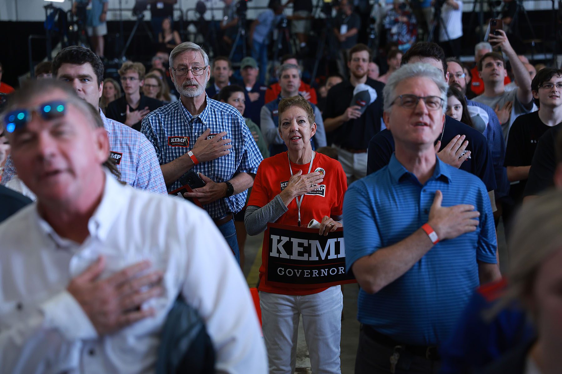 Attendees hold their hands on their hearts while they recite the Pledge of Allegiance before a campaign event.