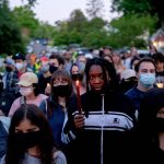 A woman holds a lit candle in the middle of a crowd of abortion rights activists.