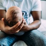 portrait of dad holding newborn baby