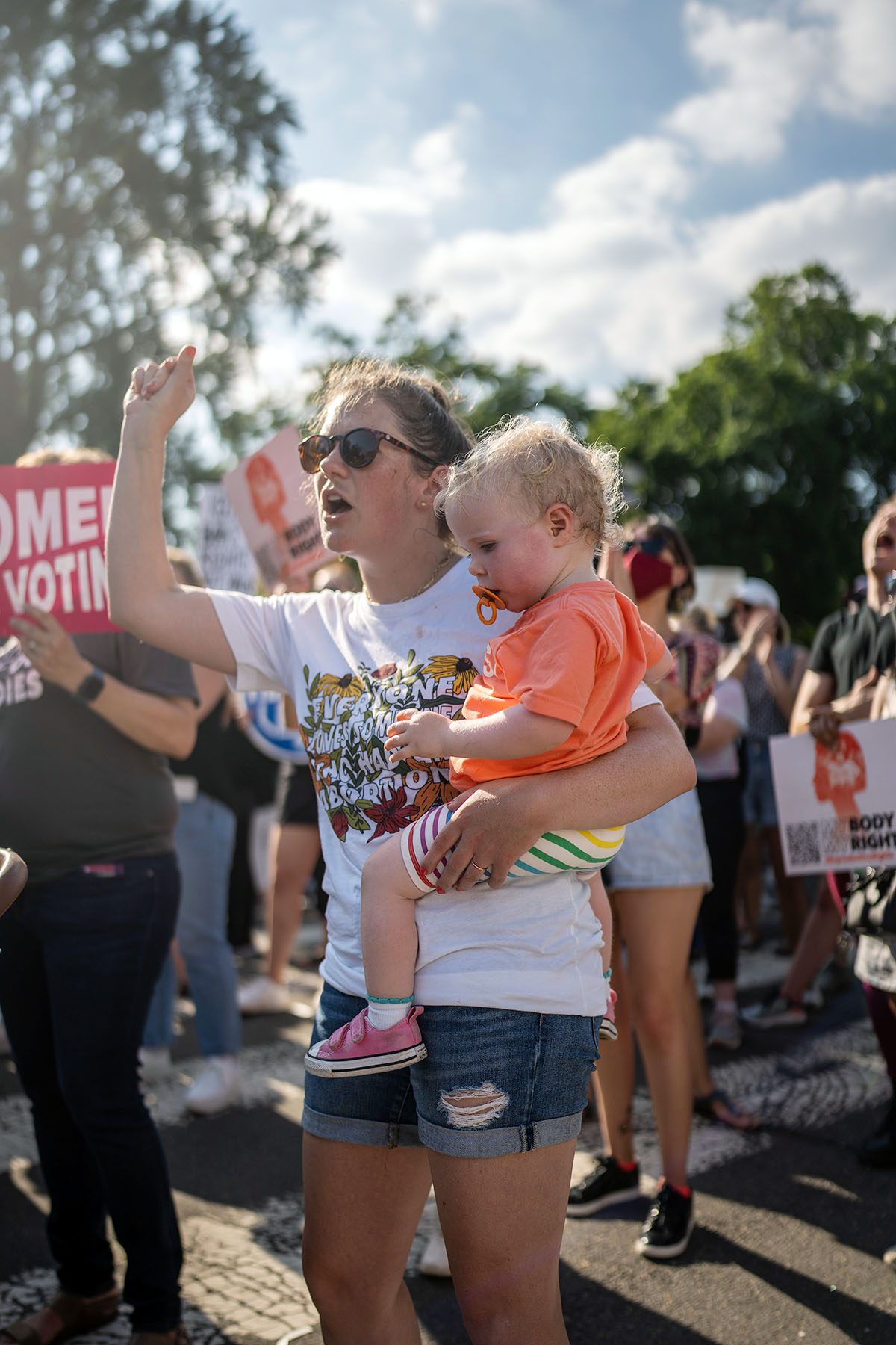 Julia Lovett holds her right fist in the air and her young daughter as she protests in front of the Supreme Court.