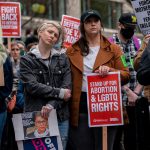 Demonstrators react during a rally while holding a sign that reads 