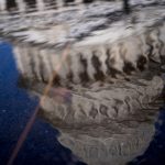 The Capitol Dome is reflected in a pool of water.