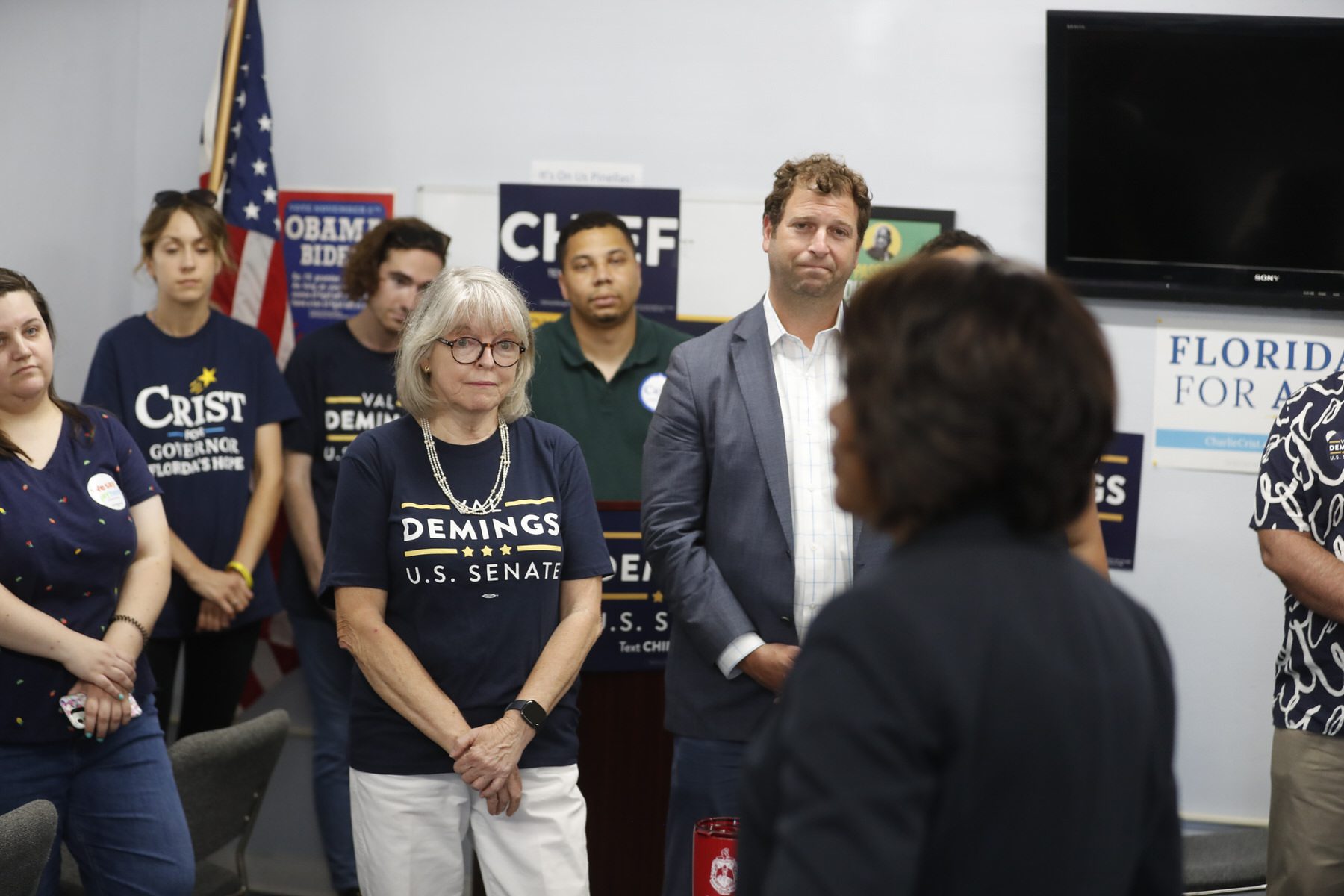 People, some of whom are wearing Val Demings for Senate shirts, listen to the candidate speak