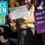 A demonstrator holds up a note that reads 