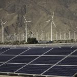 Solar panels and windmills in a desert.