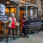 Climate activists hold signs and banners as they protest outisde BlackRock headquarters.