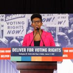 Kelley Robinson speaks at a podium during a press conference following the Peace Walk in celebration of Martin Luther King Jr. Day.