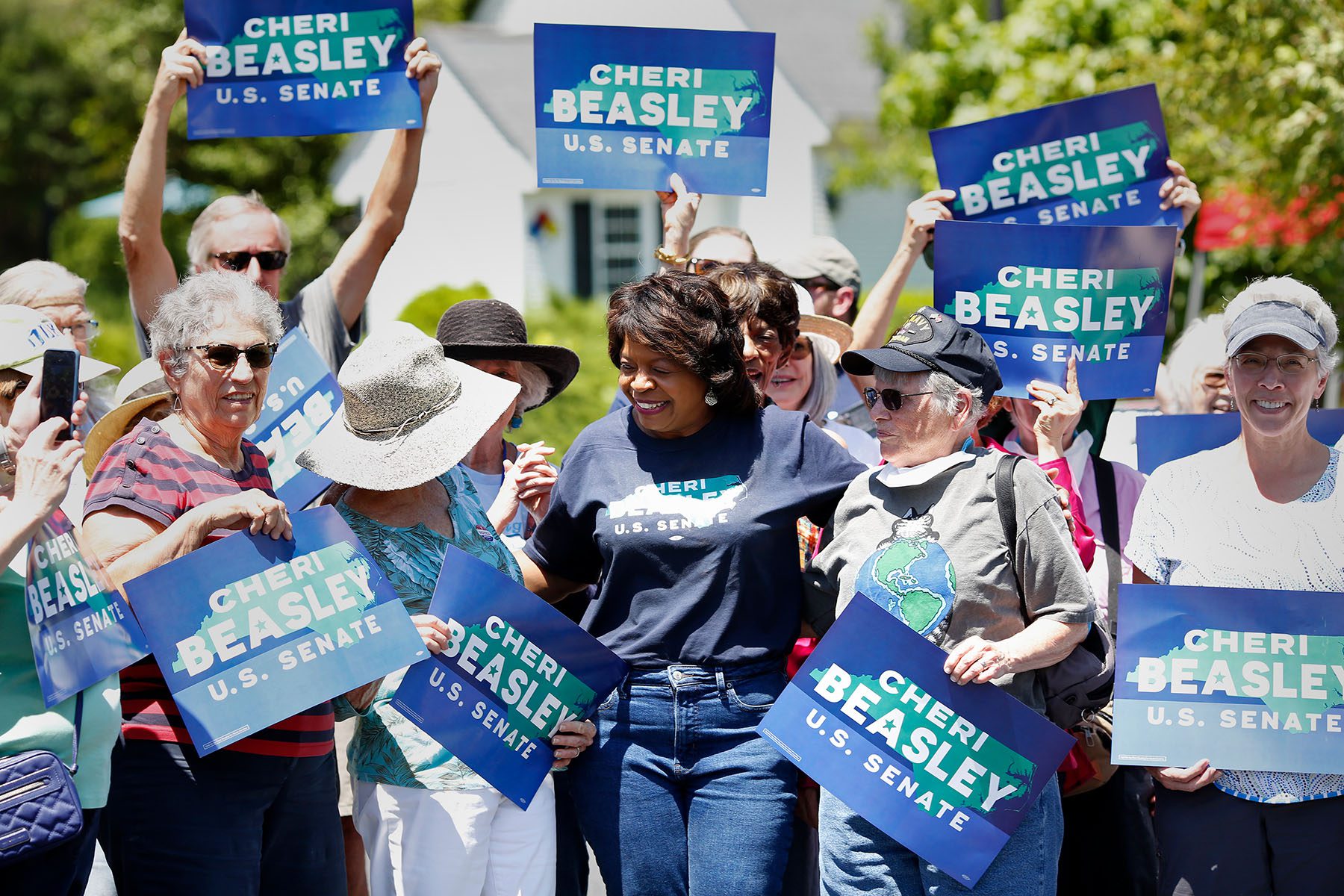 Cheri Beasley laughs after posing for a photograph with voters holding "Cheri Beasley for Senate" signs near a polling place.