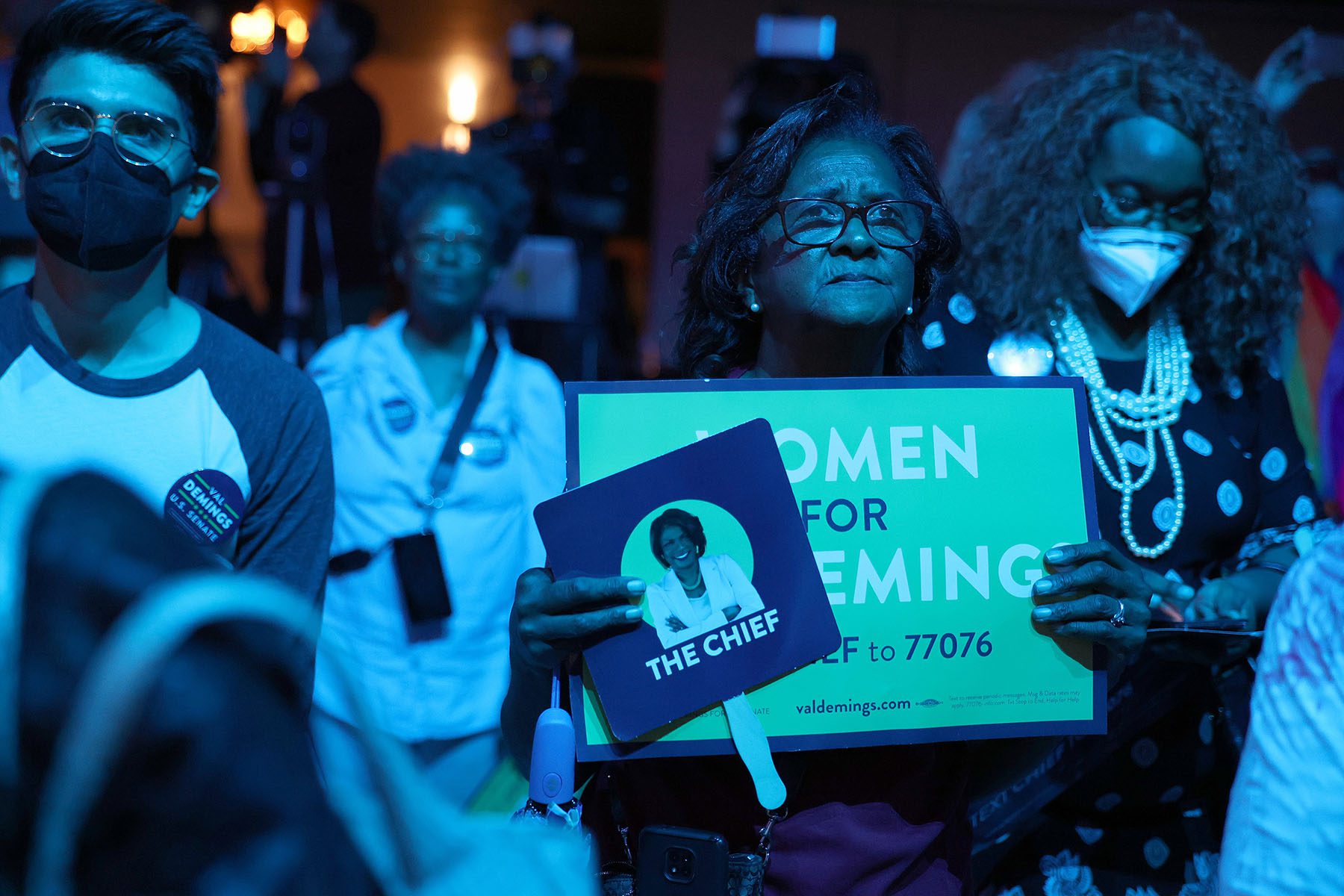 A Demings supporter holds a sign that reads "women for demings" as she listens to speeches at a campaign event.