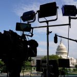 A camera and lights are set up near the U.S. Capitol.