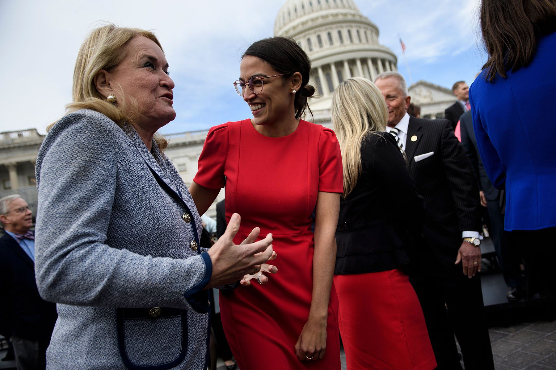 Alexandria Ocasio-Cortez laughs and chats with colleagues on Capitol Hill.
