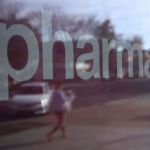 A pedestrian is reflected in the window of a CVS Pharmacy.