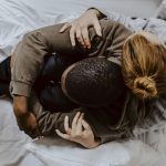 Mother embracing depressed son on bed at home.