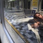 A woman rests on a man's shoulder as they ride a Los Angeles Metro Rail train.