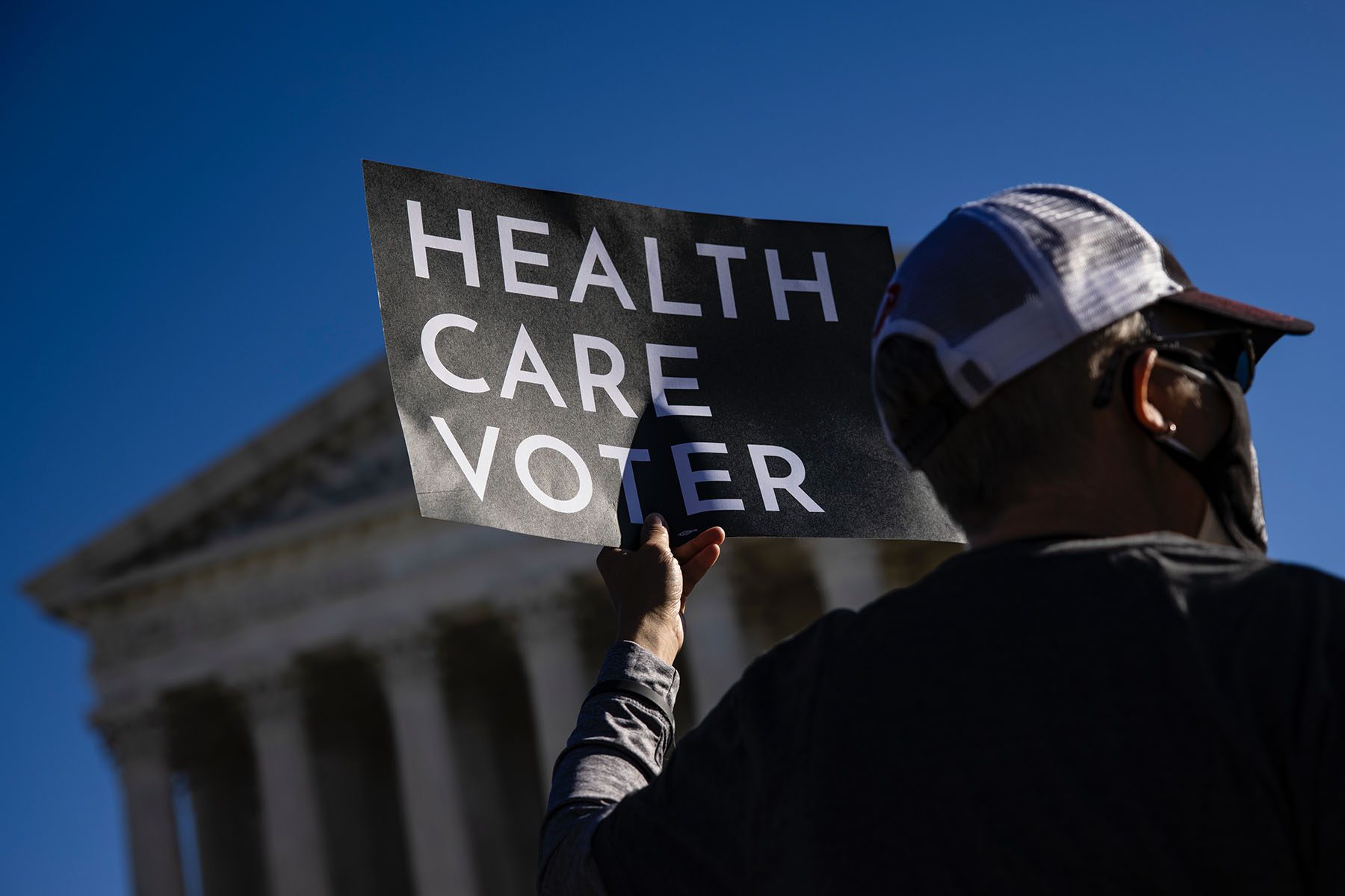 A supporter of the Affordable Care Act holds a sign that reads "Health Care Voter" as he protests in front of the Supreme Court.