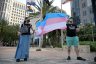 Two activists hold a flag at a rally to protect transgender kids.