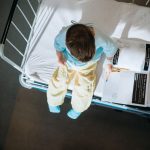 Little boy sitting on a hospital bed coloring a book.