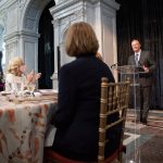 Second Gentleman Doug Emhoo stands in front of first lady Dr. Jill Biden and others and delivers a speech.