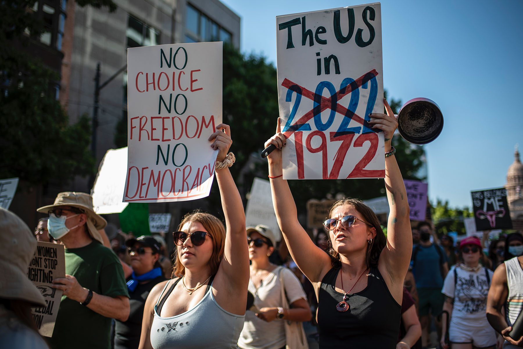 Protesters march while holding signs during an abortion-rights rally in Austin, Texas. The signs read "No choice, no freedom, no democracy" and "The US in 2022 [crossed out] 1972"