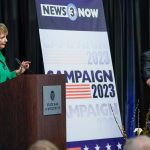 Janet Protasiewicz and Dan Kelly stand at lecterns with a sign between them that says Campaign 2023 at the only one-on-one debate