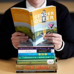 Student sitting behind a stack of books.