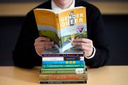 Student sitting behind a stack of books.