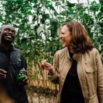 Kamala Harris laughs with a farmer while visting Panuka Farm just outside the city of Lusaka, Zambia.