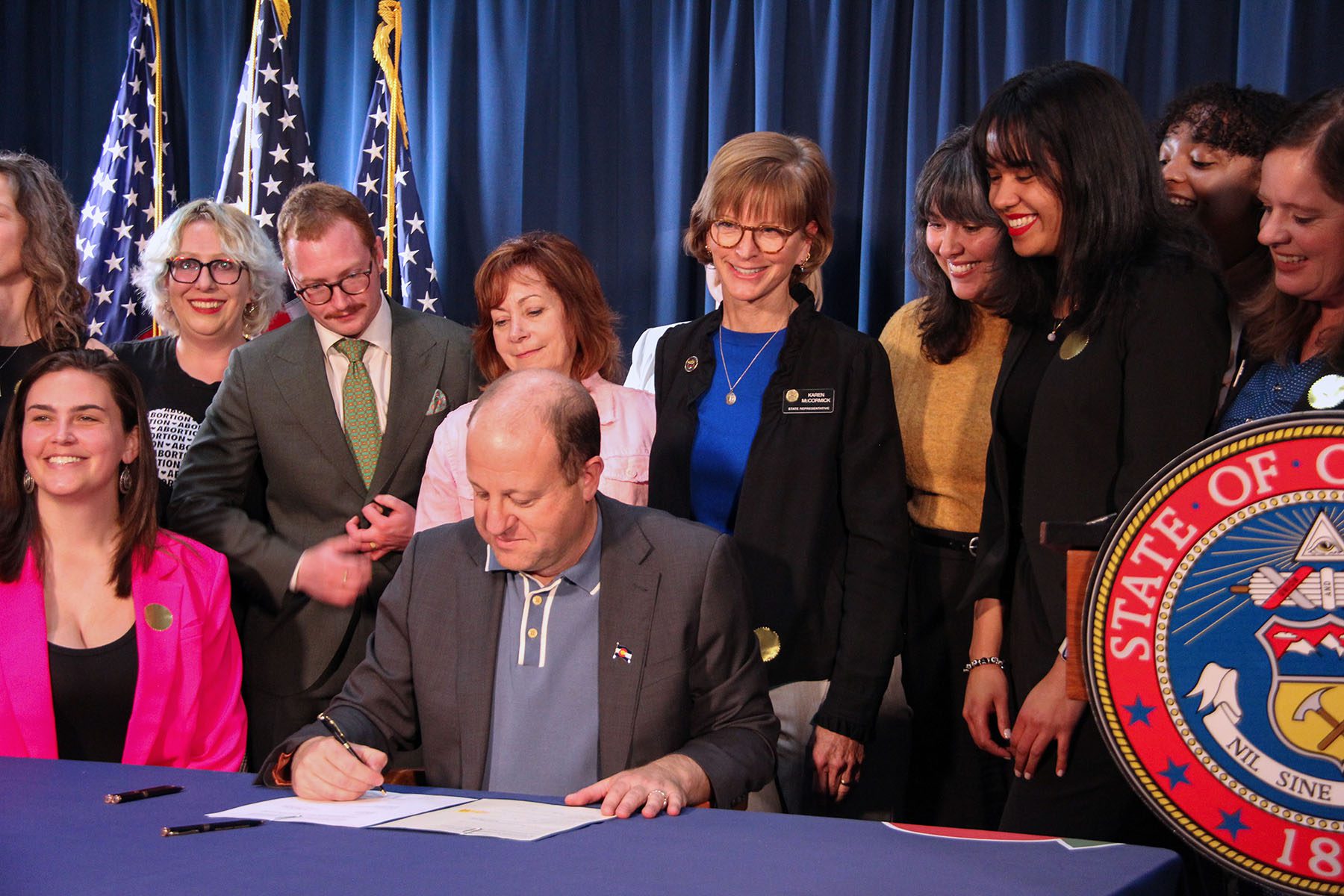 Colorado Gov. Jared Polis, surrounded by abortion rights advocates and legislators, signs Senate Bill 23-190.
