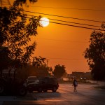 A high schooler walks towards a bus stop as the sun rises above Main St.