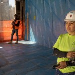 A female construction worker stands near two male workers during a ceremony to mark the completion of a new building.