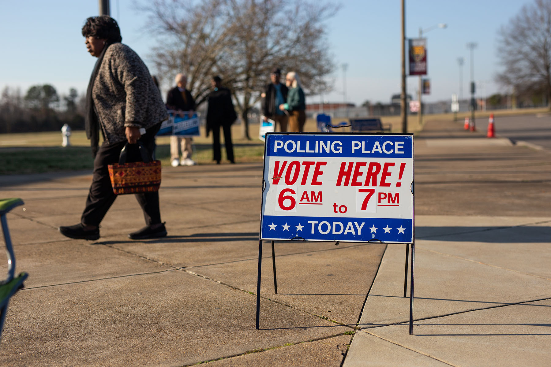 A sign that reads "Polling Place: vote here!" stands near a polling station