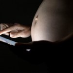 Pregnant woman using a digital tablet in dark.