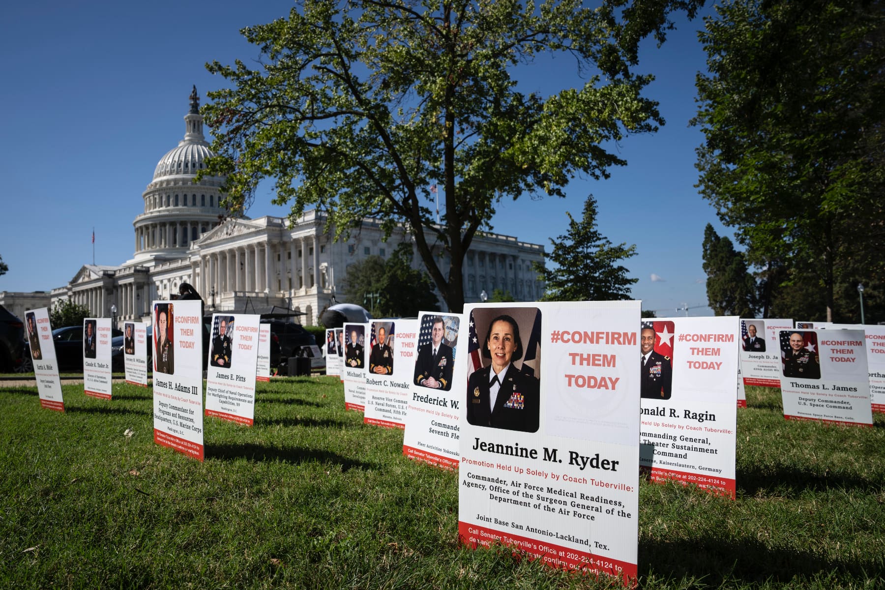 Signs saying "#Confirm them today" with photos and information about service members sit on the lawn at the U.S. Capitol