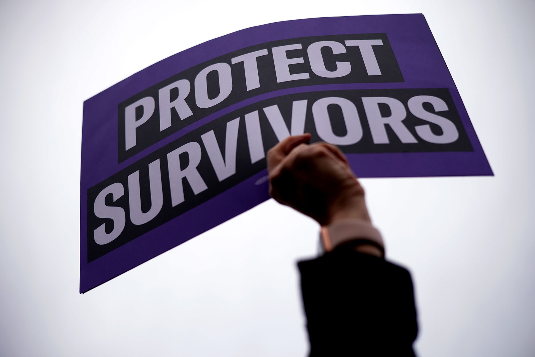 An activist holds up a sign that reads "Protect Survivors" outside U.S. Supreme Court during a gun-control rally.