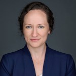 Emma Brown wears a blue jacket and smiles softly in this headshot.