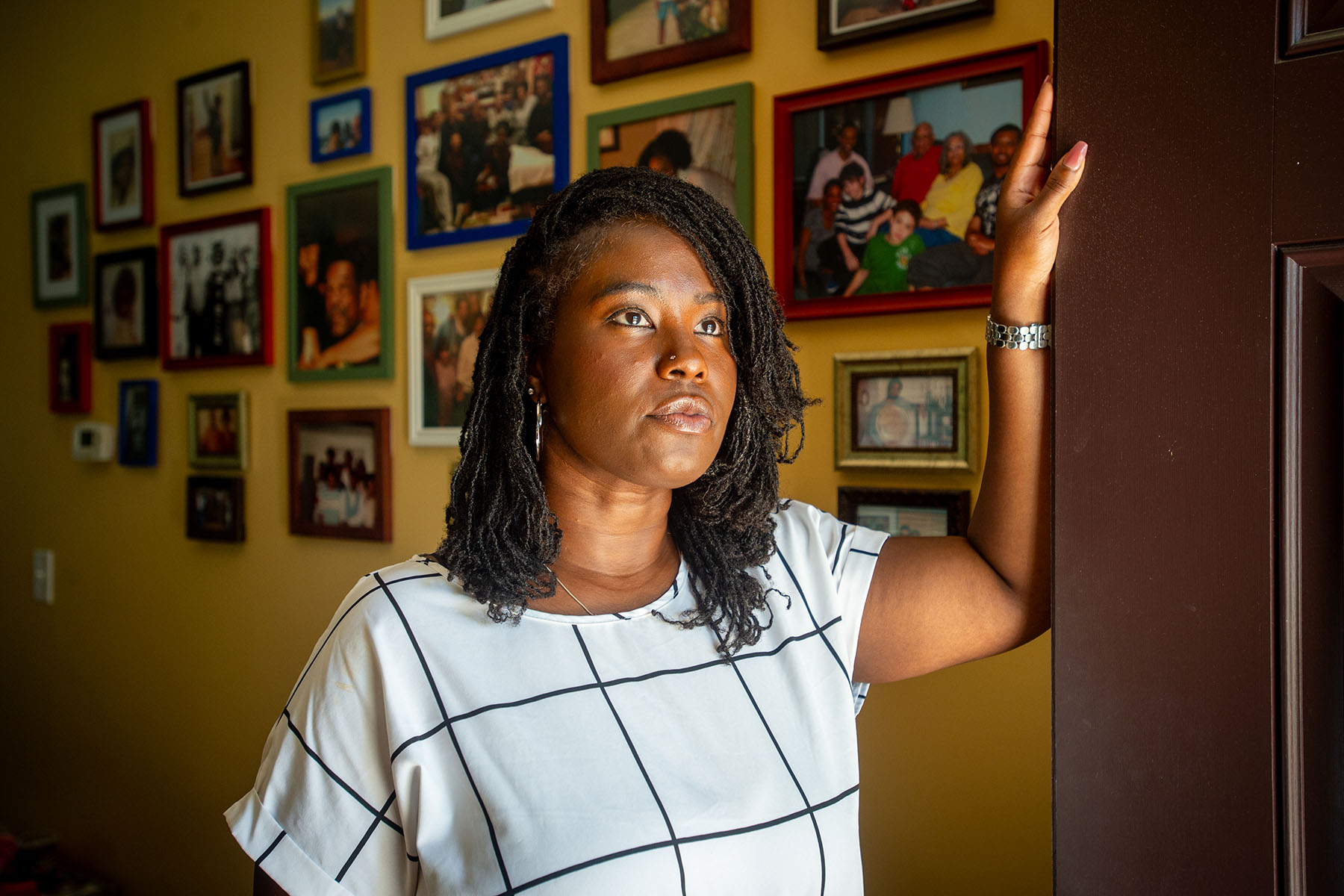 Charity Watkins stands near a doorway at her home.