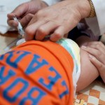 A baby receives a shot into his thigh muscle.