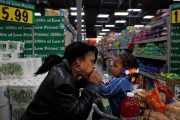 A grandmother gives their grandchild a kiss on the hand as they grocery shop together.