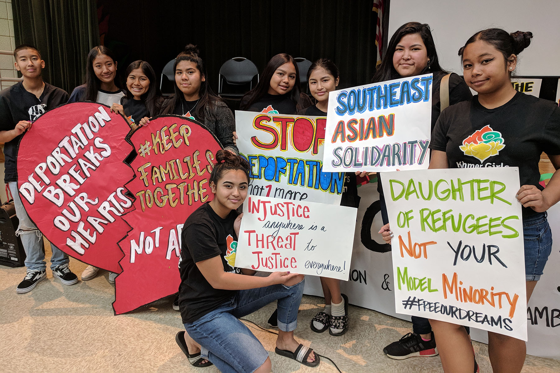 A group of young folks hold signs that read "daughter of refugees, not your model minority," "Injustice anywhere is a thread to justice everywhere," "southeast asian solidarity" and more.