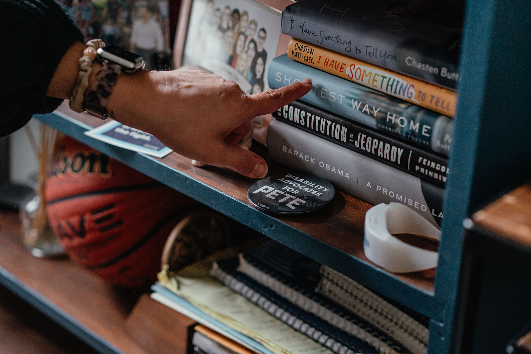 Emily Voorde points to Chasten Buttigieg's book "I have something to tell you," sitting on her shelf.