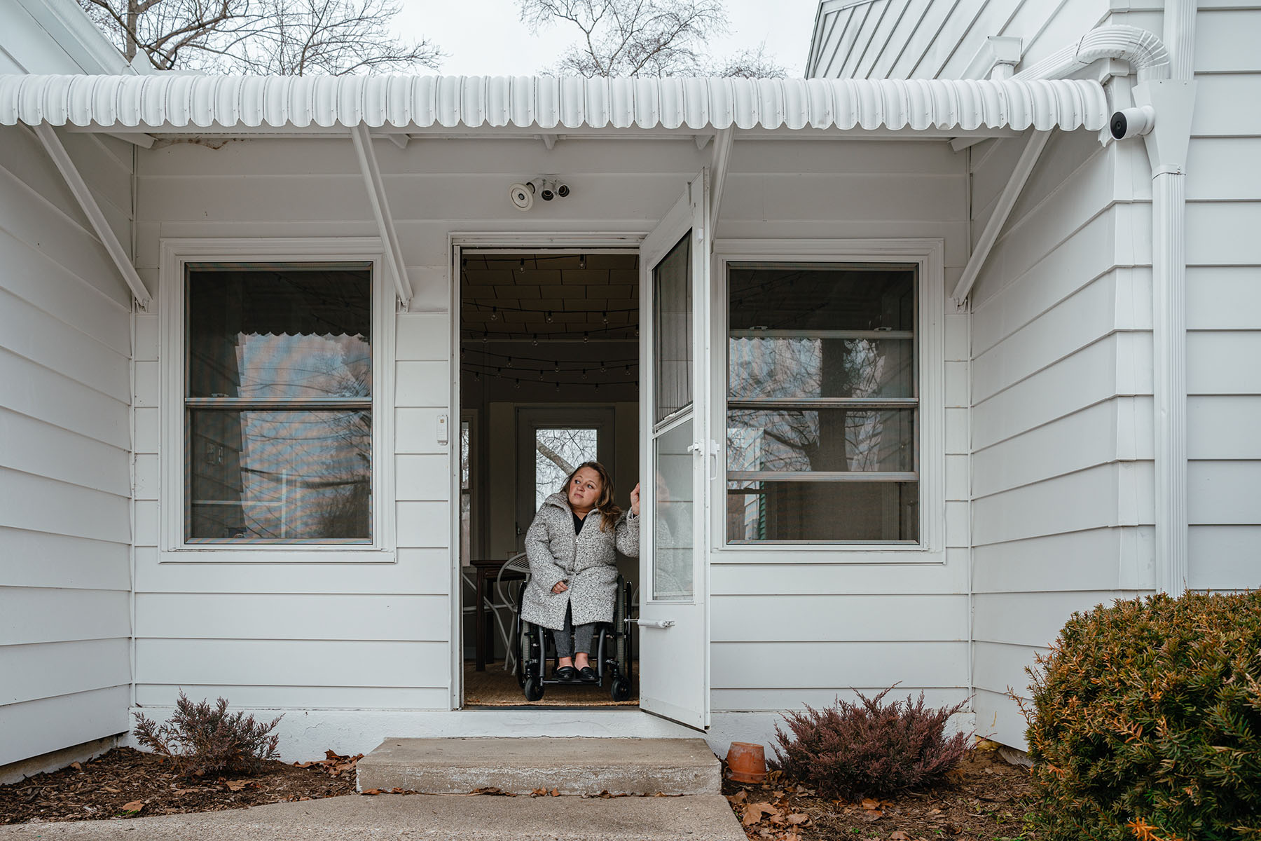 Emily Voorde sits in her wheelchair in the doorway of her home.