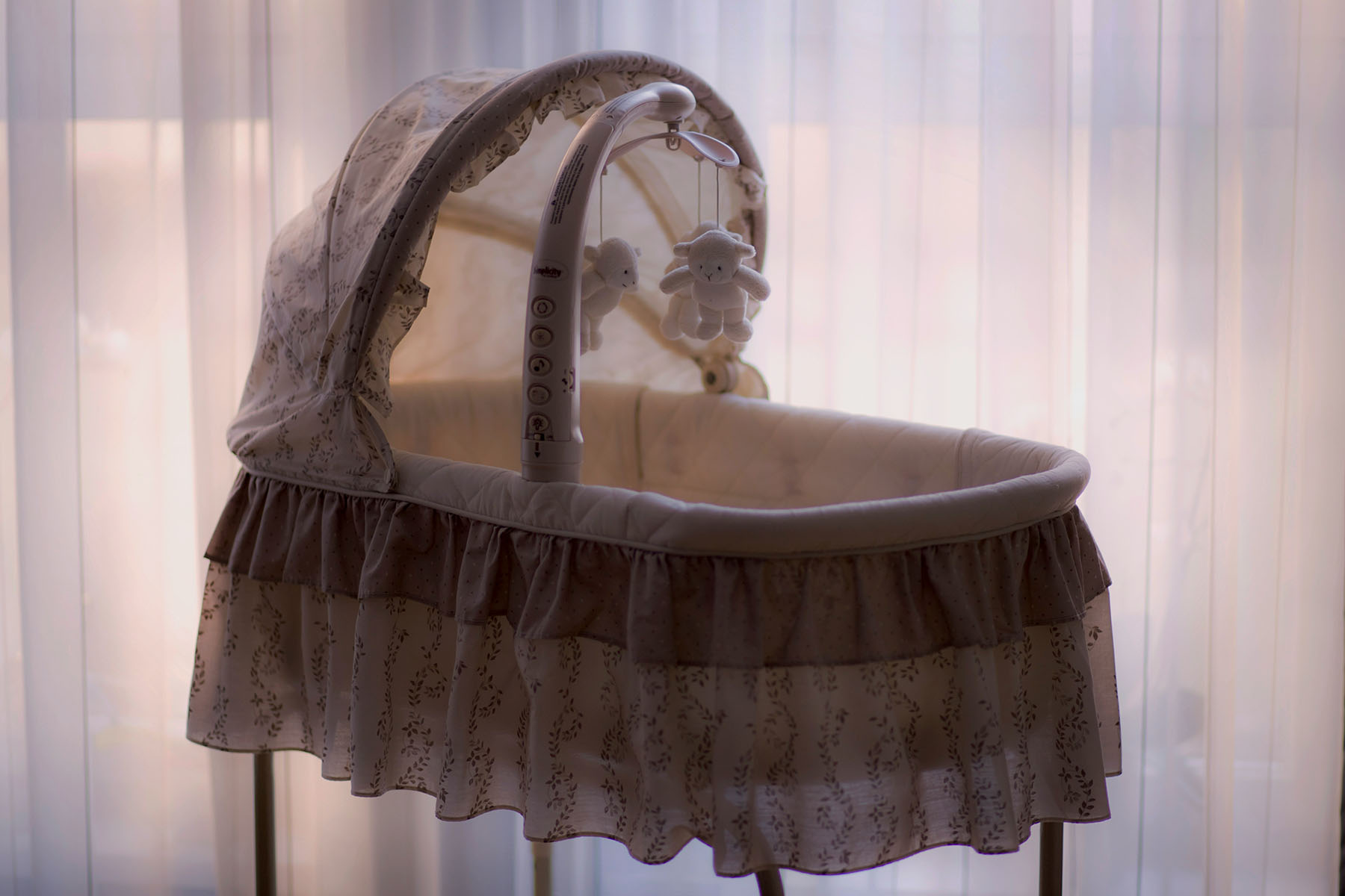 Photo of a crib with plush lambs hanging from a mobile.