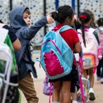 A kindergarten student gives a thumbs up to his parents as he heads to the first day of class.